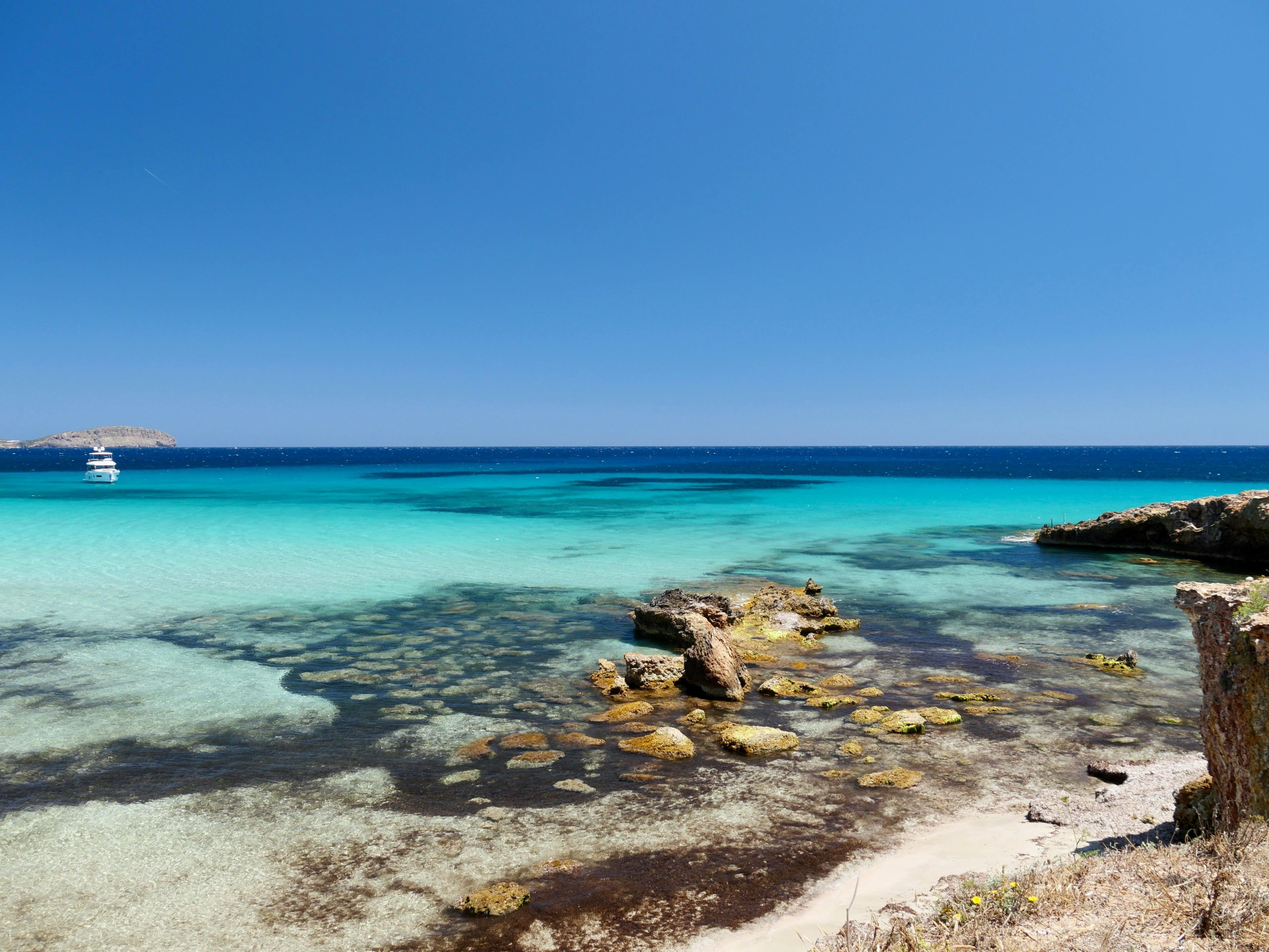 ARCIPELAGO DI LA MADDALENA A breathtaking view of Ibiza's turquoise waters and rocky coastline under a clear blue sky.