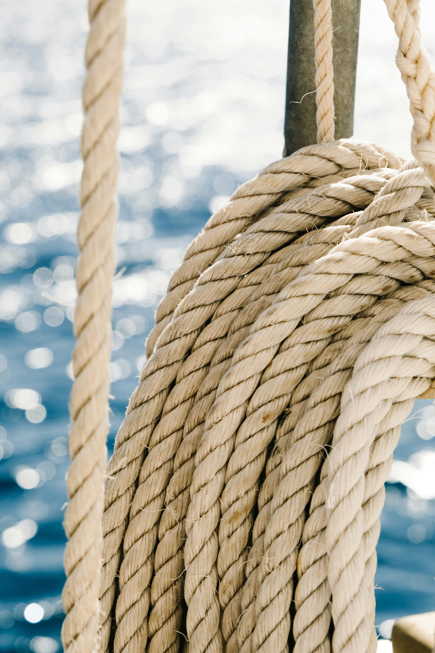 Detailed view of coiled nautical rope against a sparkling sea backdrop.